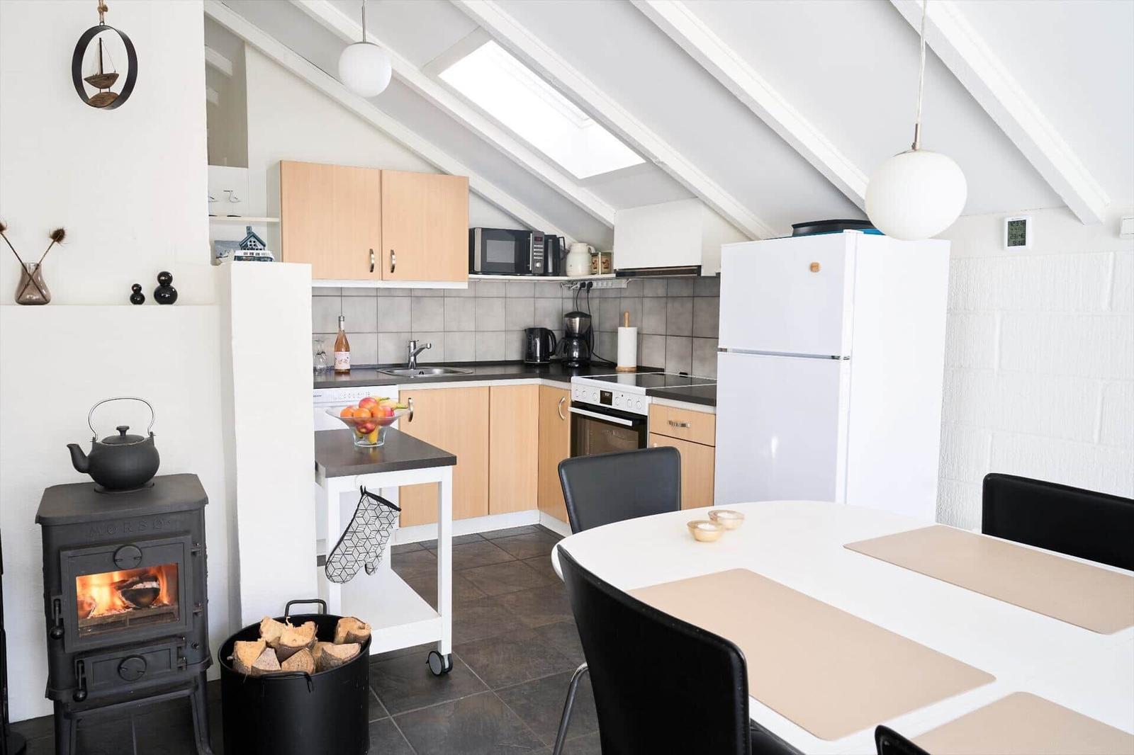Küche mit Esstisch, Kaminofen und Dachfenster.