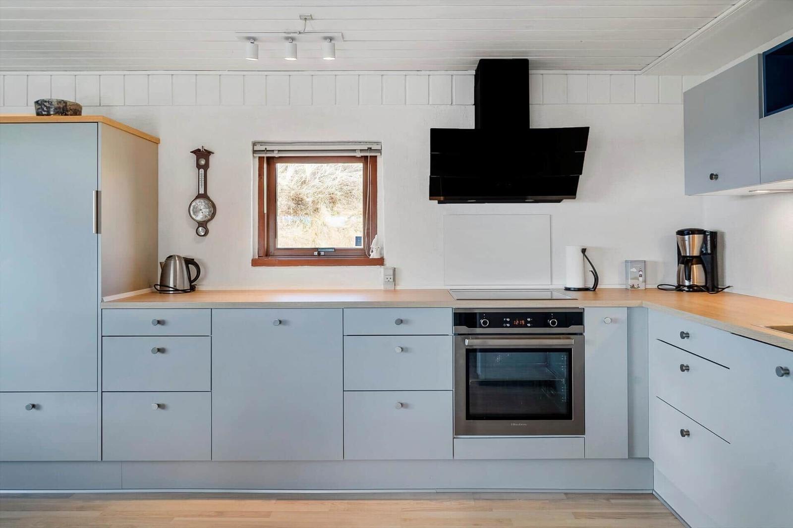 Moderne Küche mit hellen Schränken, Holzoberflächen und integriertem Backofen.