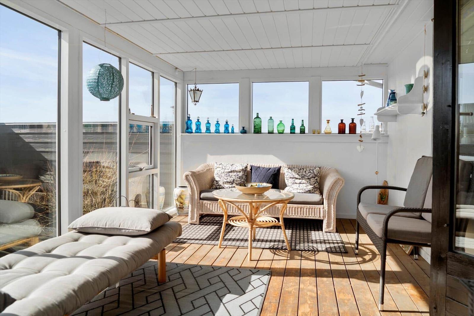 Terrasse mit Sitzgruppe, Glasflaschenregal und Holzboden