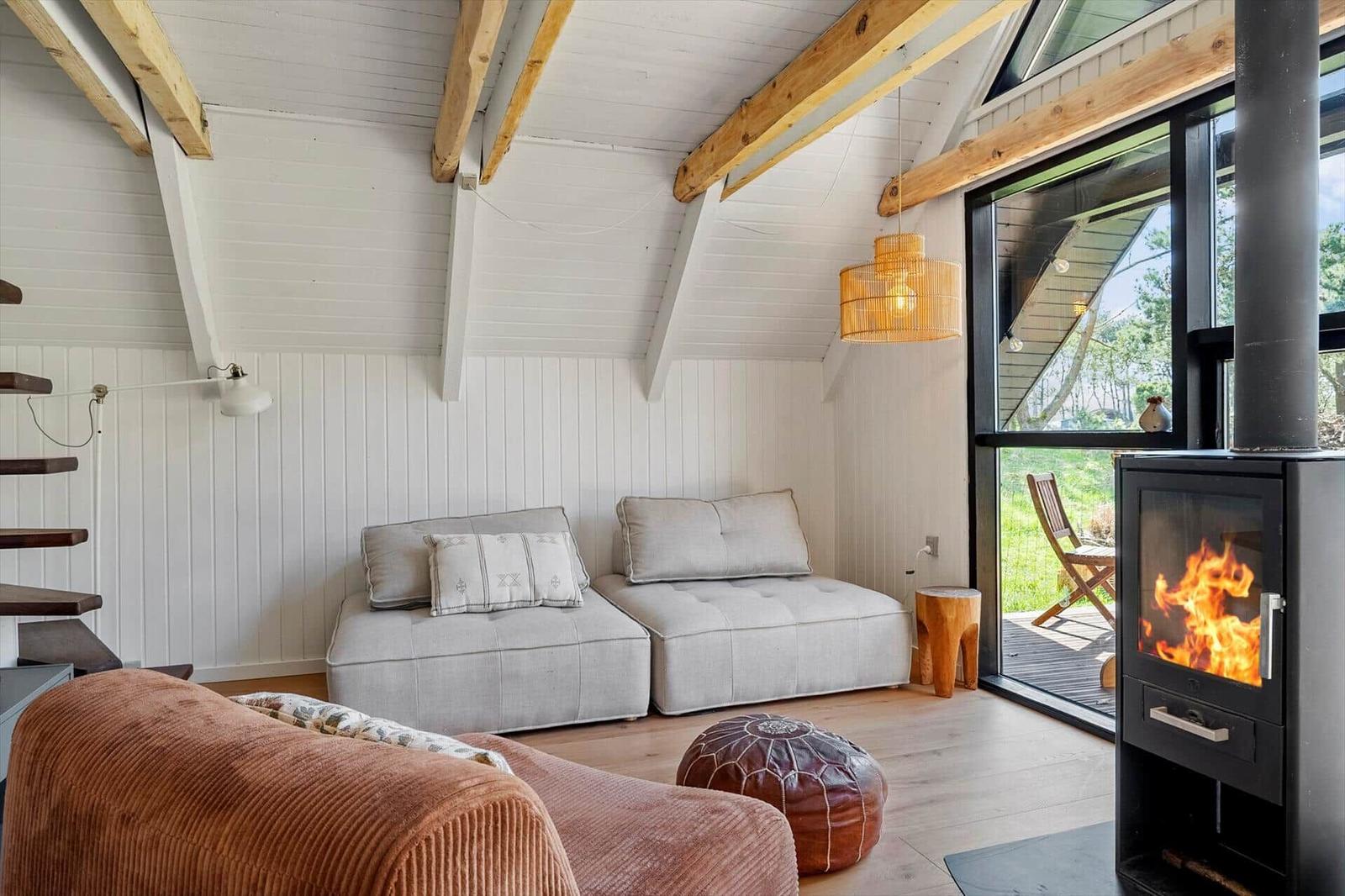 Wohnraum mit Sofa, Kamin und Glasfront zum Garten