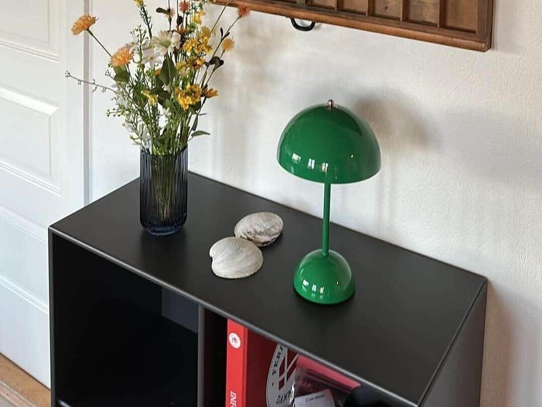Schwarzer Tisch mit grüner Lampe, Blumen und Muscheln.