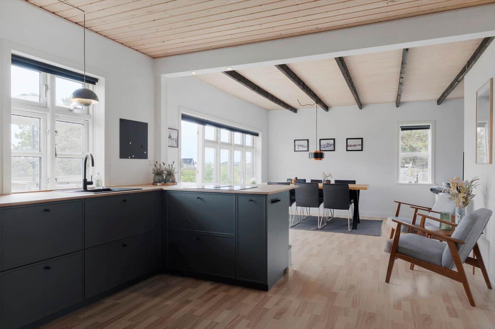 Küche mit Essbereich und Sitzgelegenheit. Holzdecke mit Balken, Fenster und moderne Einrichtung.