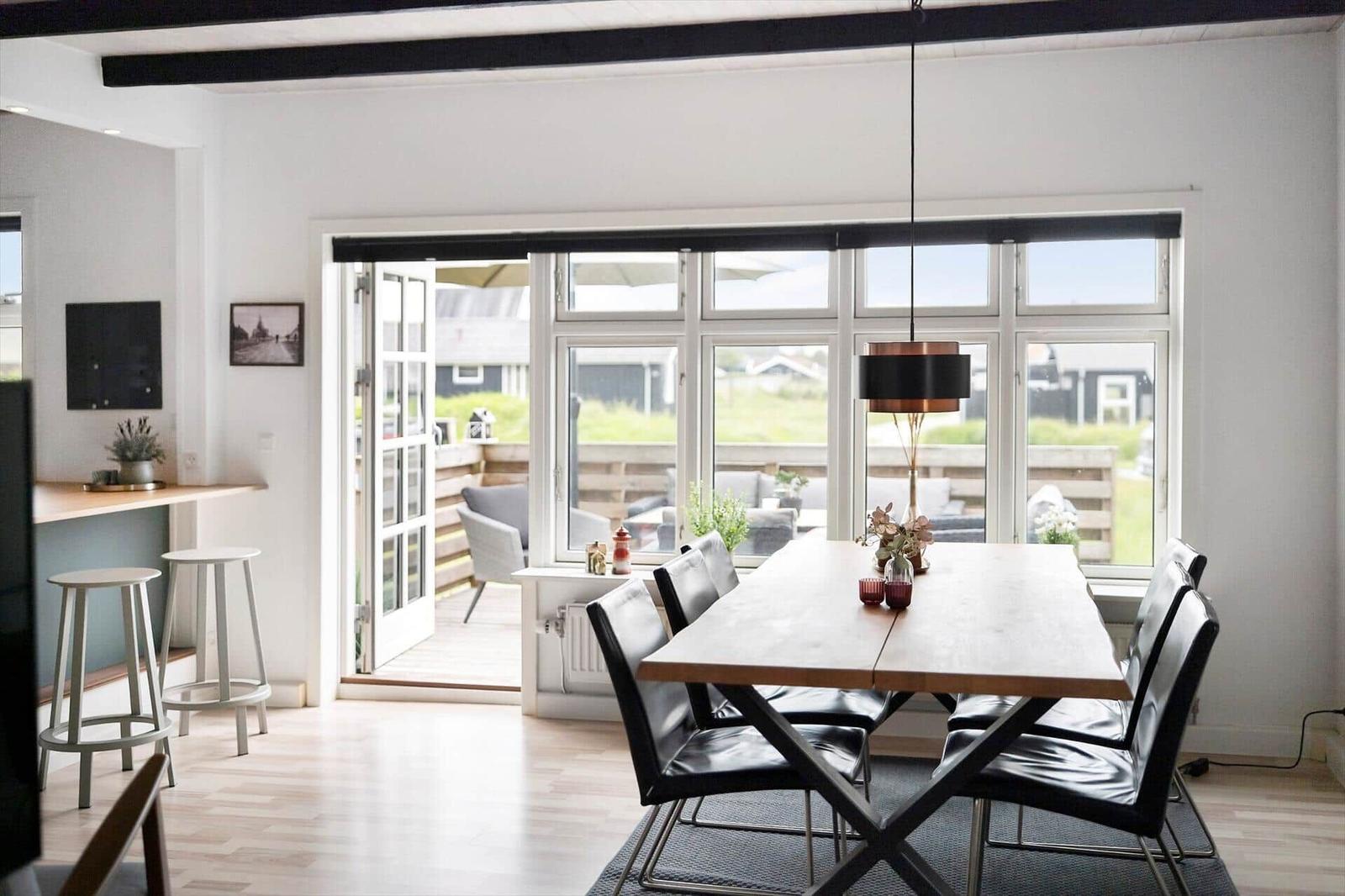 Esszimmer mit Holztisch, schwarzen Stühlen und Blick auf die Terrasse.