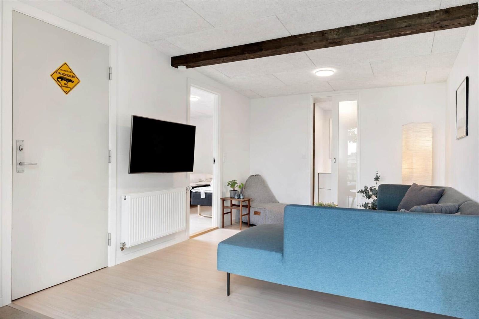 Wohnzimmer mit blauem Sofa, Fernseher und Holzbalken an der Decke.