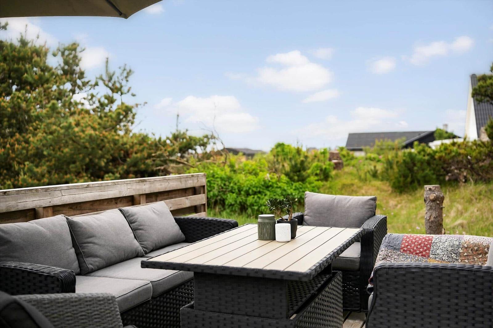 Terrasse mit Sitzgruppe, Tisch und Blick auf Grünflächen.