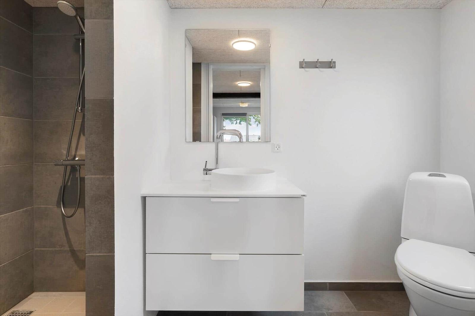 Badezimmer mit Dusche, Waschbecken und Toilette. Moderne Einrichtung.