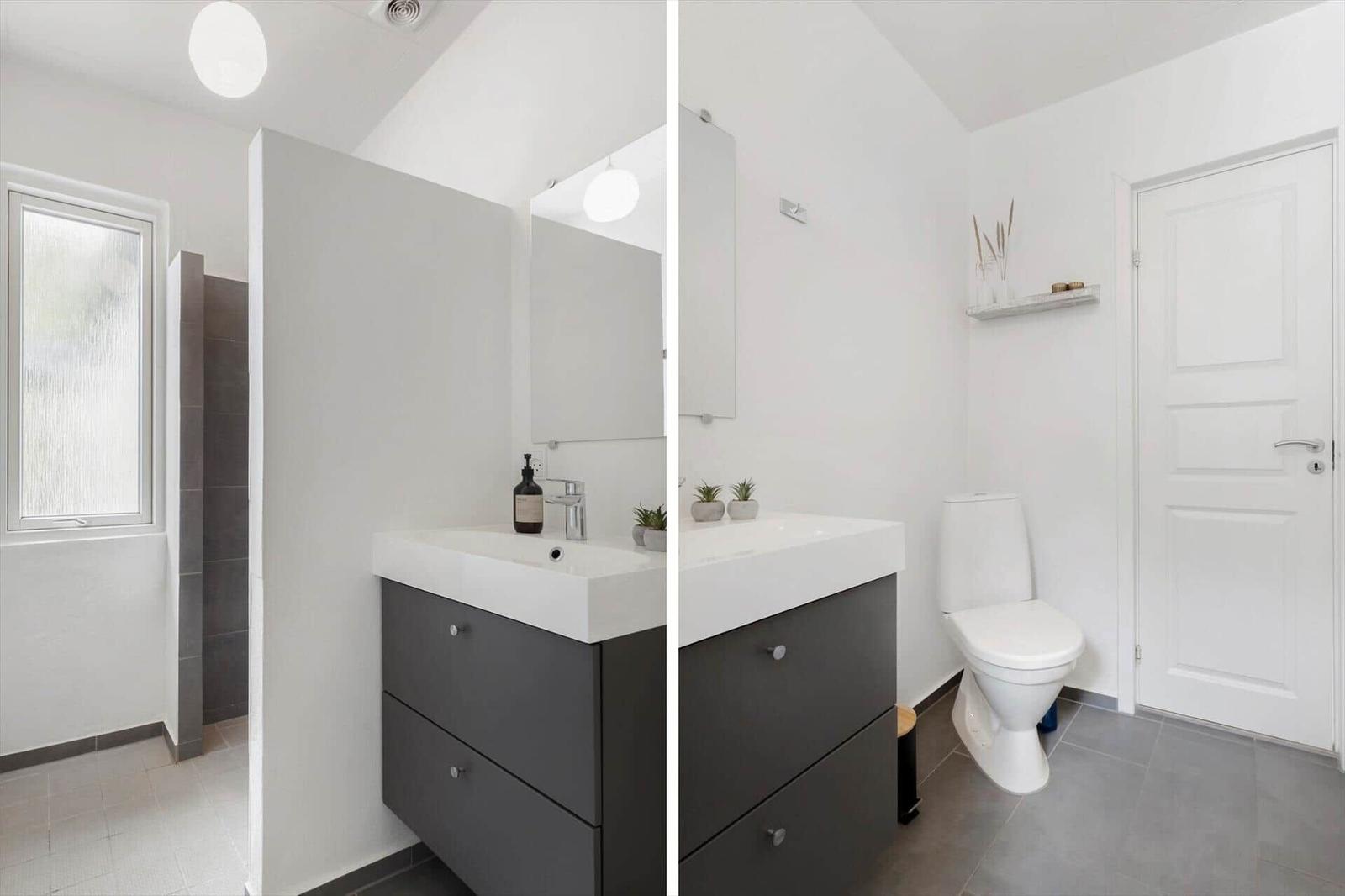 Badezimmer mit Waschbecken, Toilette und Dusche. Weiße Wände, graue Fliesen und moderne Einrichtung.