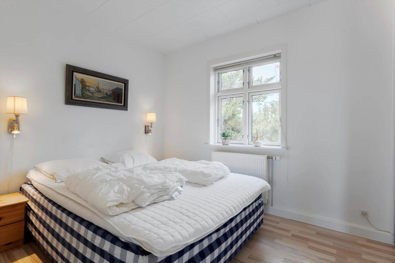 Schlafzimmer mit Bett, Fenster und Wandbild.