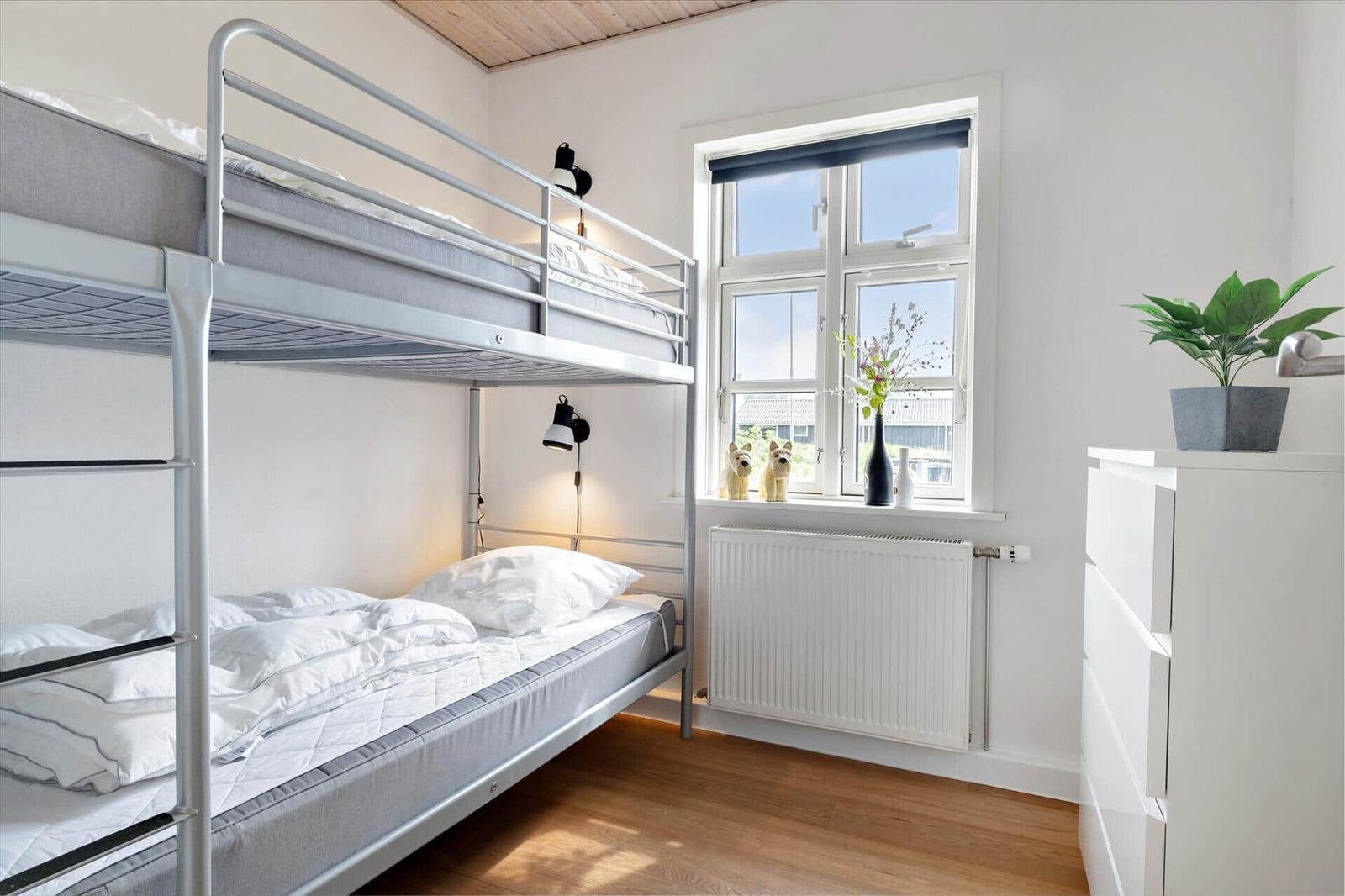 Zimmer mit Doppelstockbett, Fenster, Heizkörper und Schrank.