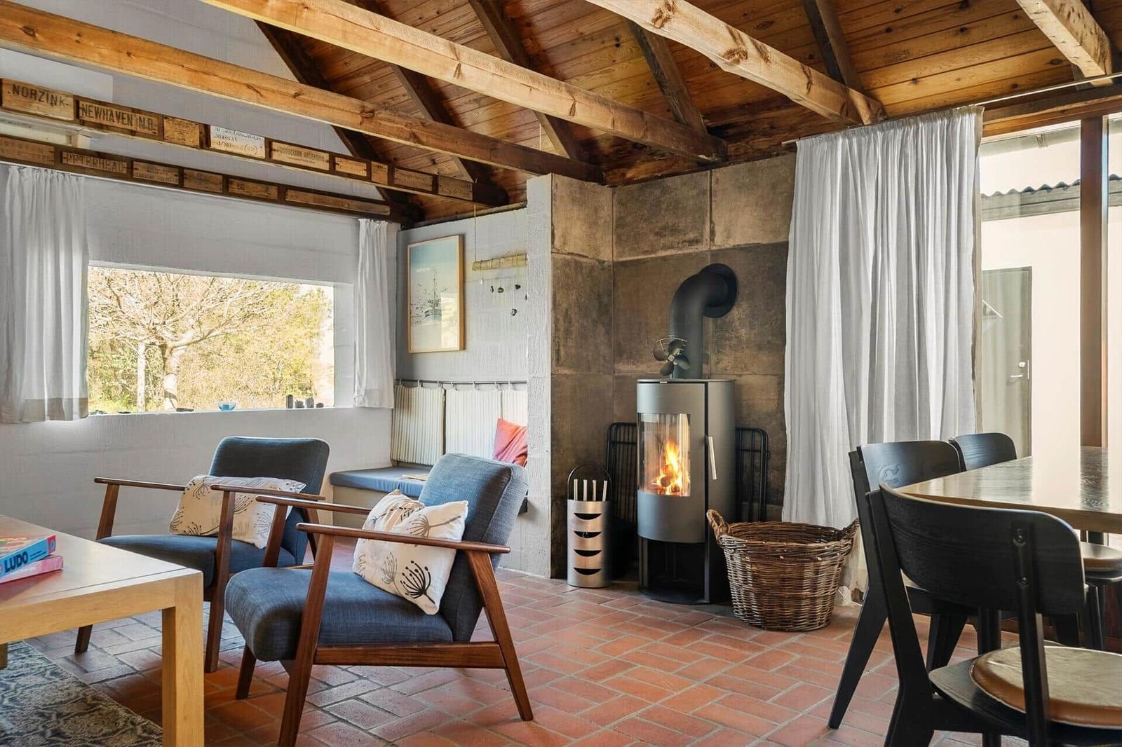 Wohnraum mit Kamin, Sitzgelegenheiten und Blick auf Außenbereich.
