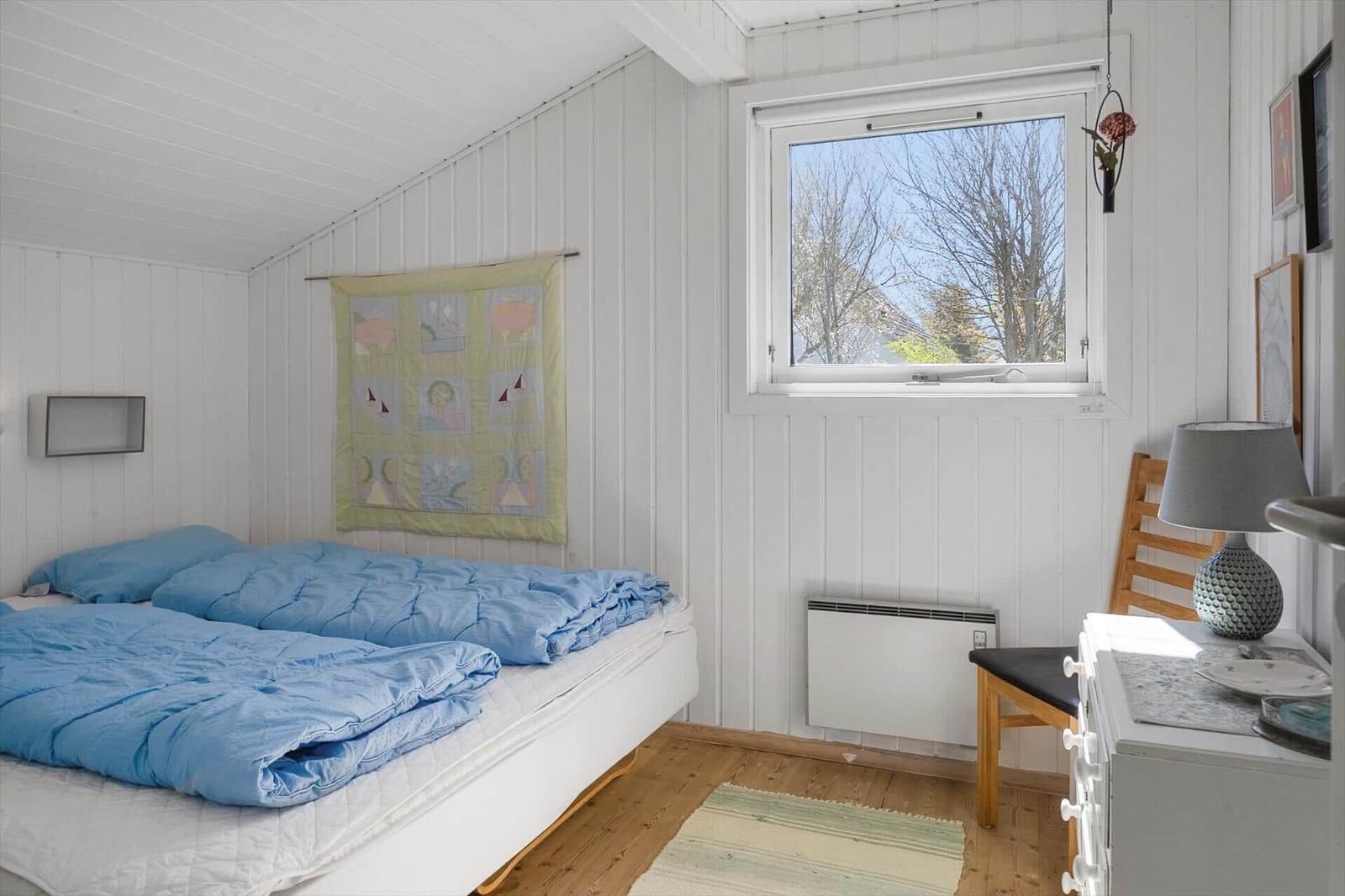 Schlafzimmer mit Bett, Fenster und Kleiderschrank.