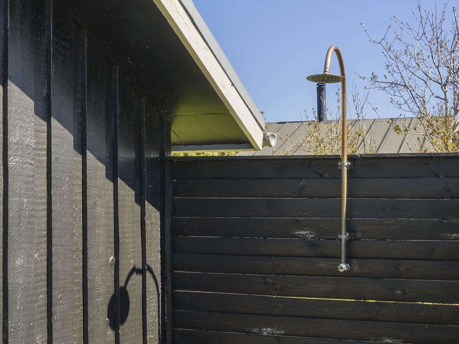 Außen-Dusche an schwarzer Holzwand unter blauem Himmel