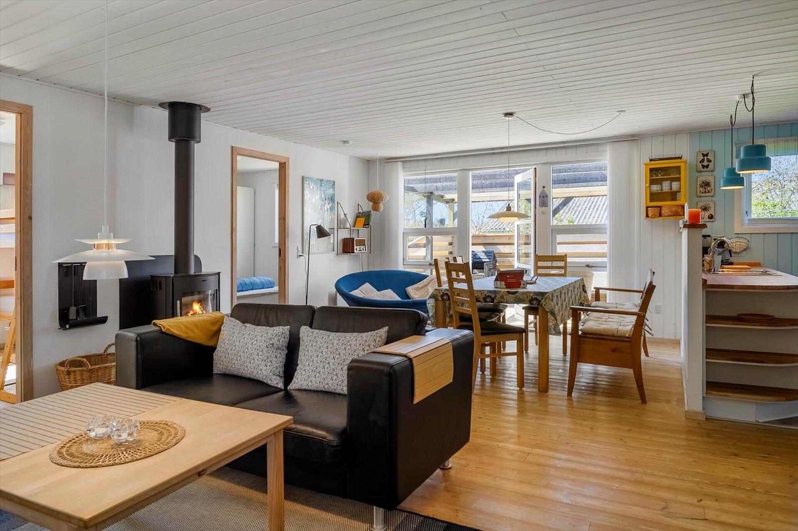 Wohn- und Essbereich mit Kamin, Sofa und Holzboden. Durchgang zu Schlafzimmer.
