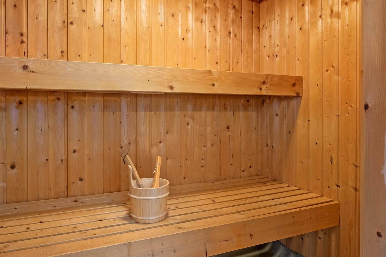 Sauna mit Holzbank und Eimer mit Besen