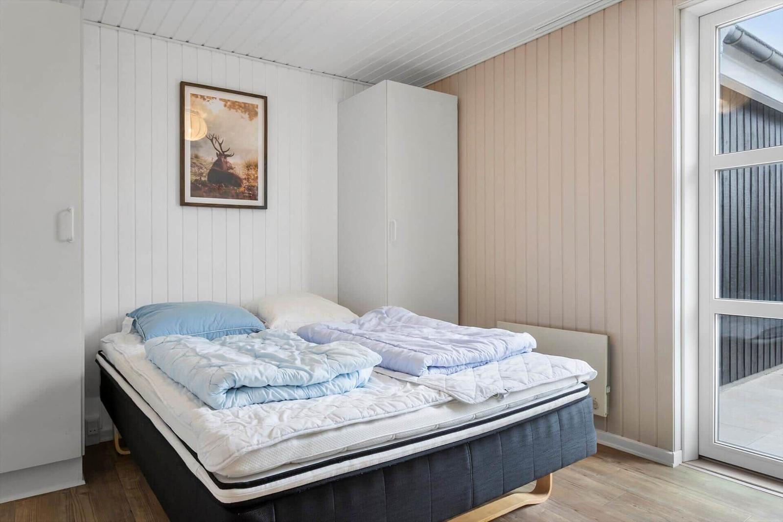 Bedroom with bed, wardrobe, and picture on wall. Door leads to balcony.