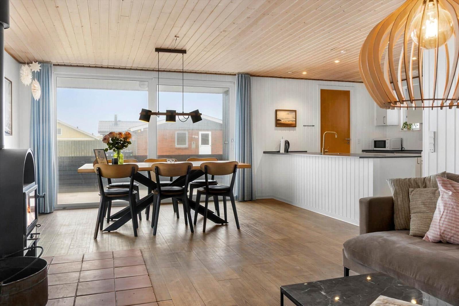 Living and dining area with wooden floor, seating, and kitchen counter.