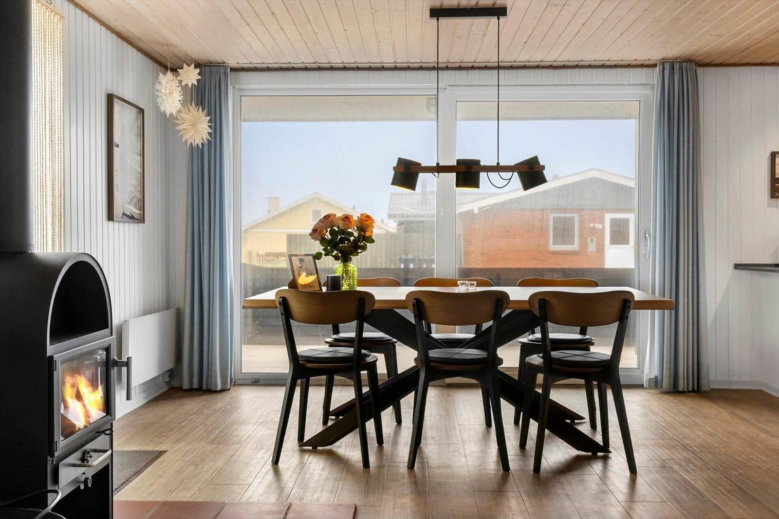 Dining room with table, chairs, and fireplace. Large window view outside.