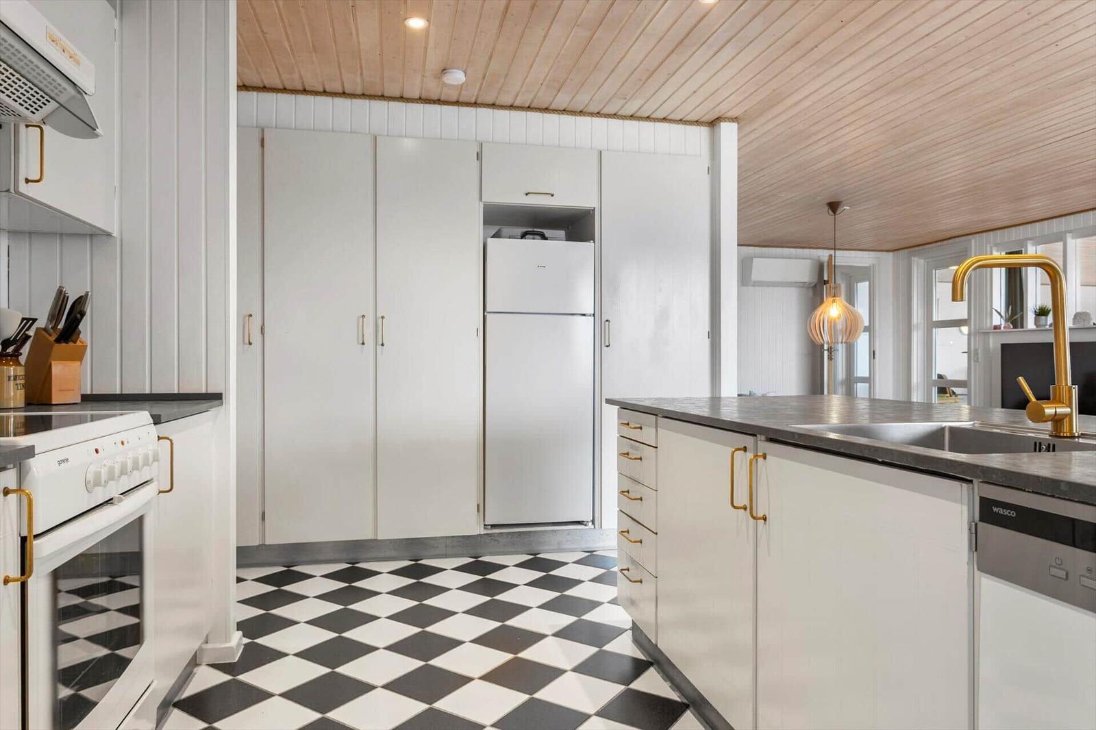 Kitchen with white cabinets, gold handles, and black-and-white checkered floor tiles.