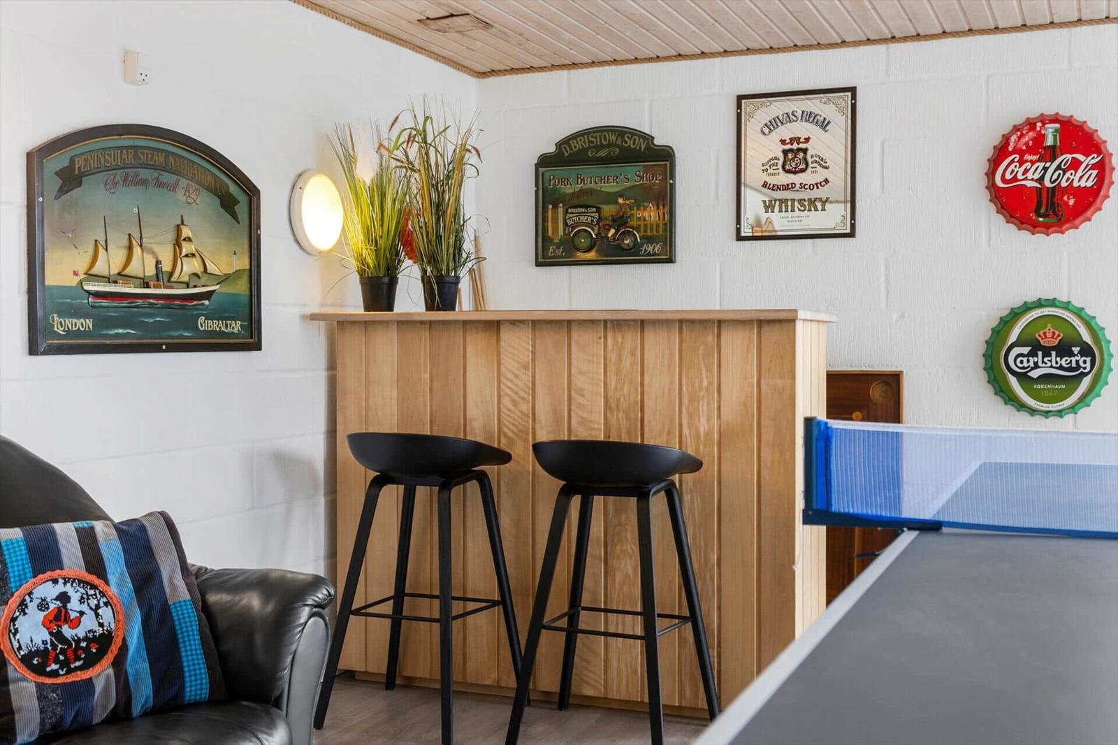 Bar area with ping pong table and stools against wall decor.