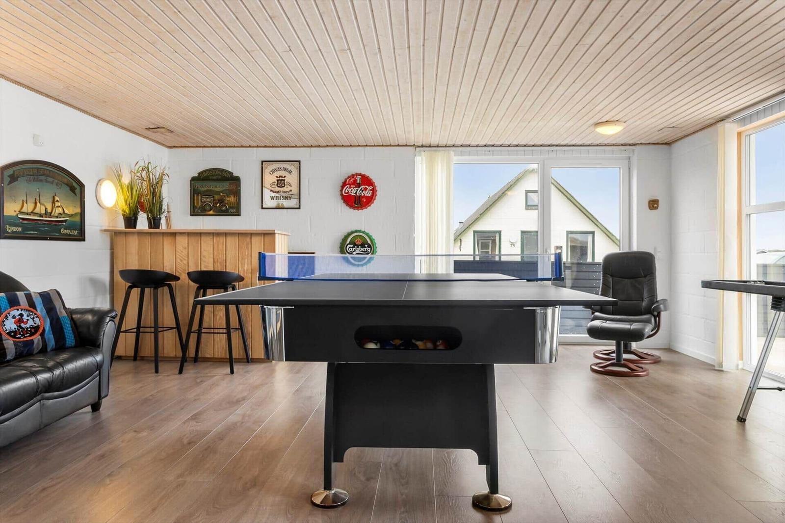 Room with ping pong table, bar and seating. Large windows with view outside.