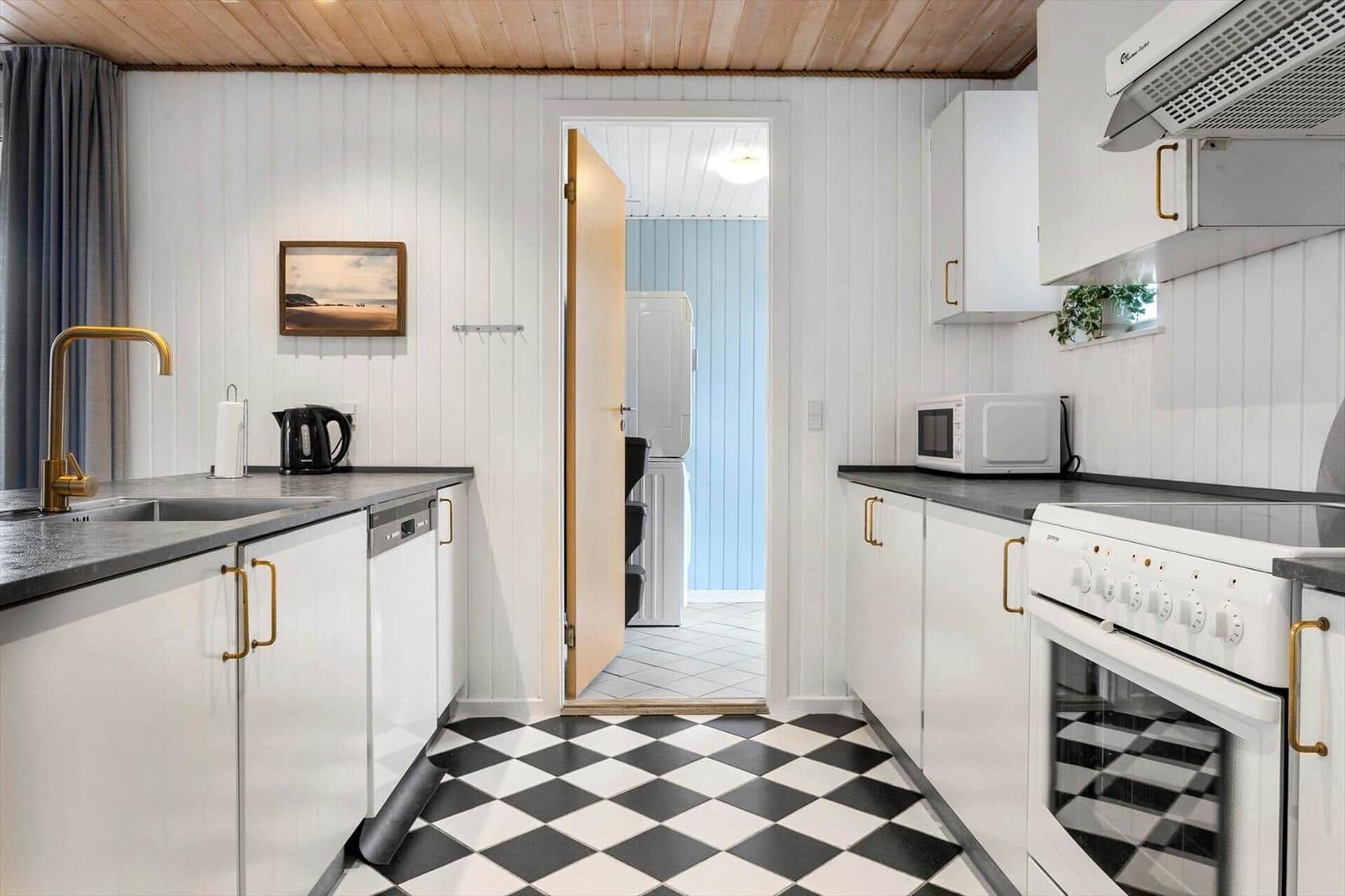 Kitchen with white cabinets, black-and-white floor, and gold handles.