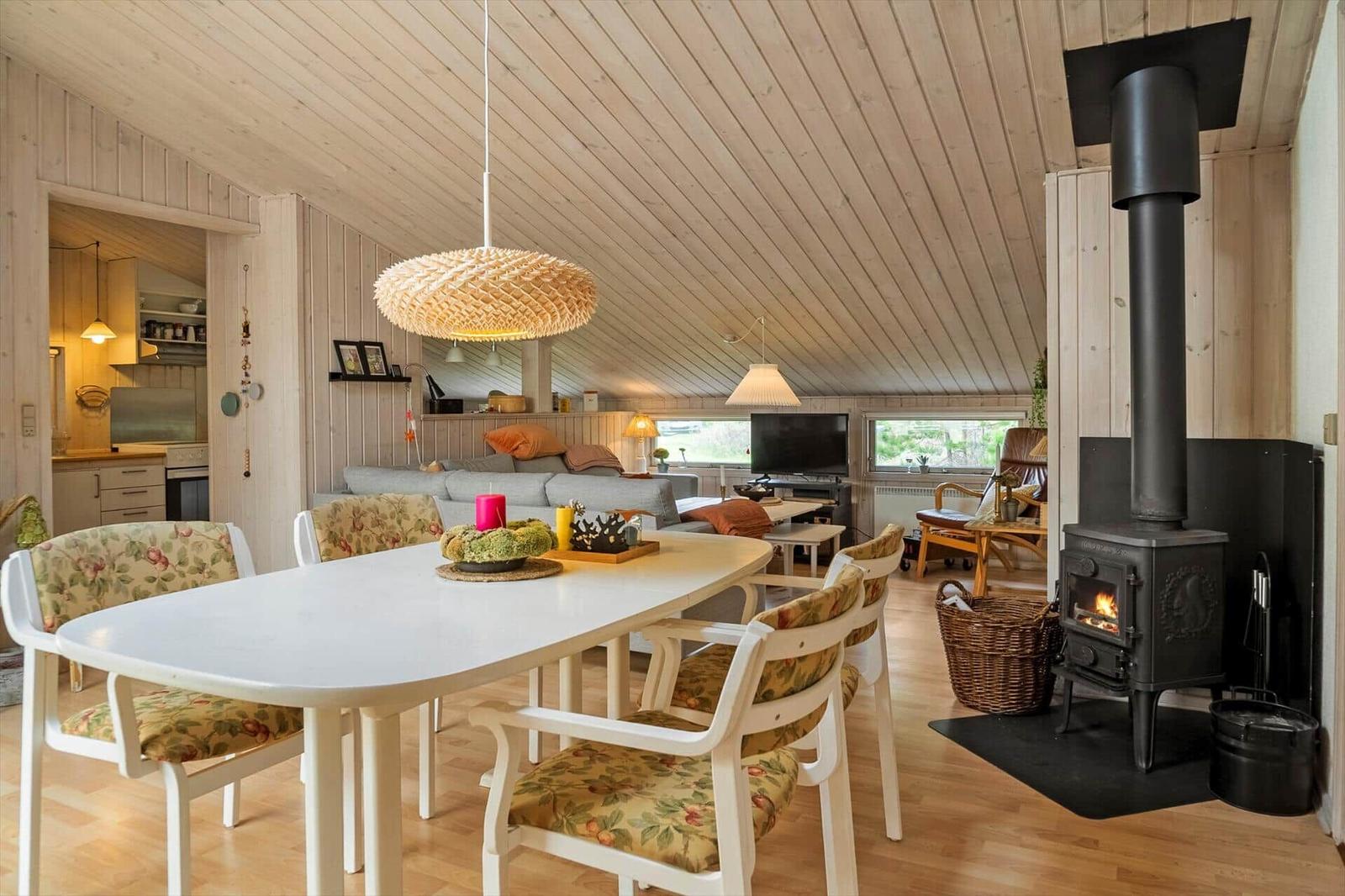 Essbereich mit Tisch und Stühlen, Kamin und Wohnbereich mit Sofa und TV.