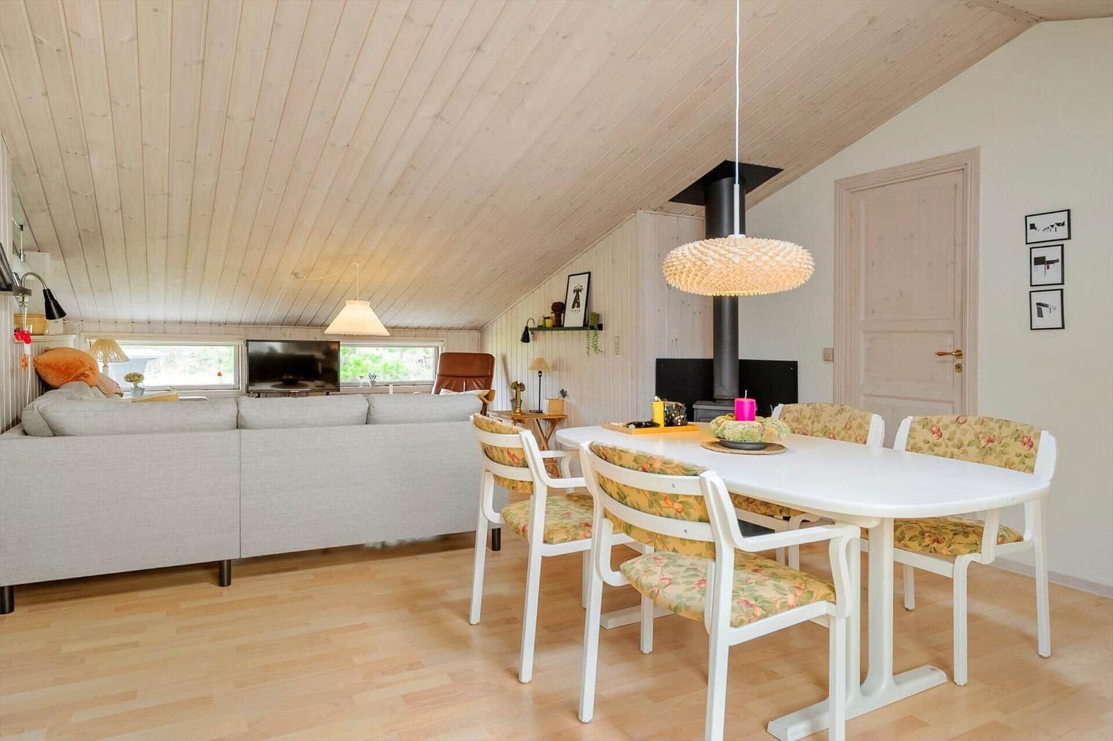 Wohn- und Essbereich mit Sofa, Esstisch und Holzdecke.