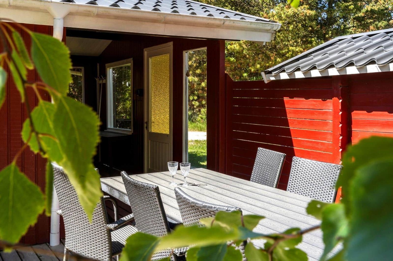 Roter Holzaussenbereich mit Tisch und Stühlen. Tür und Fenster sind sichtbar.