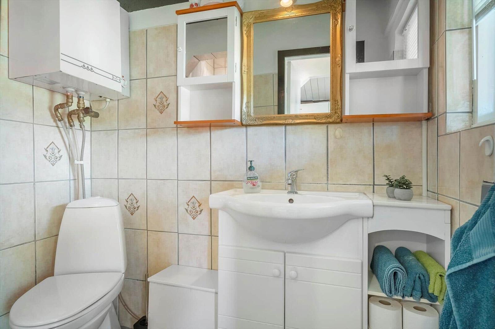 Badezimmer mit Waschbecken, Spiegel, Toilette und Handtüchern.