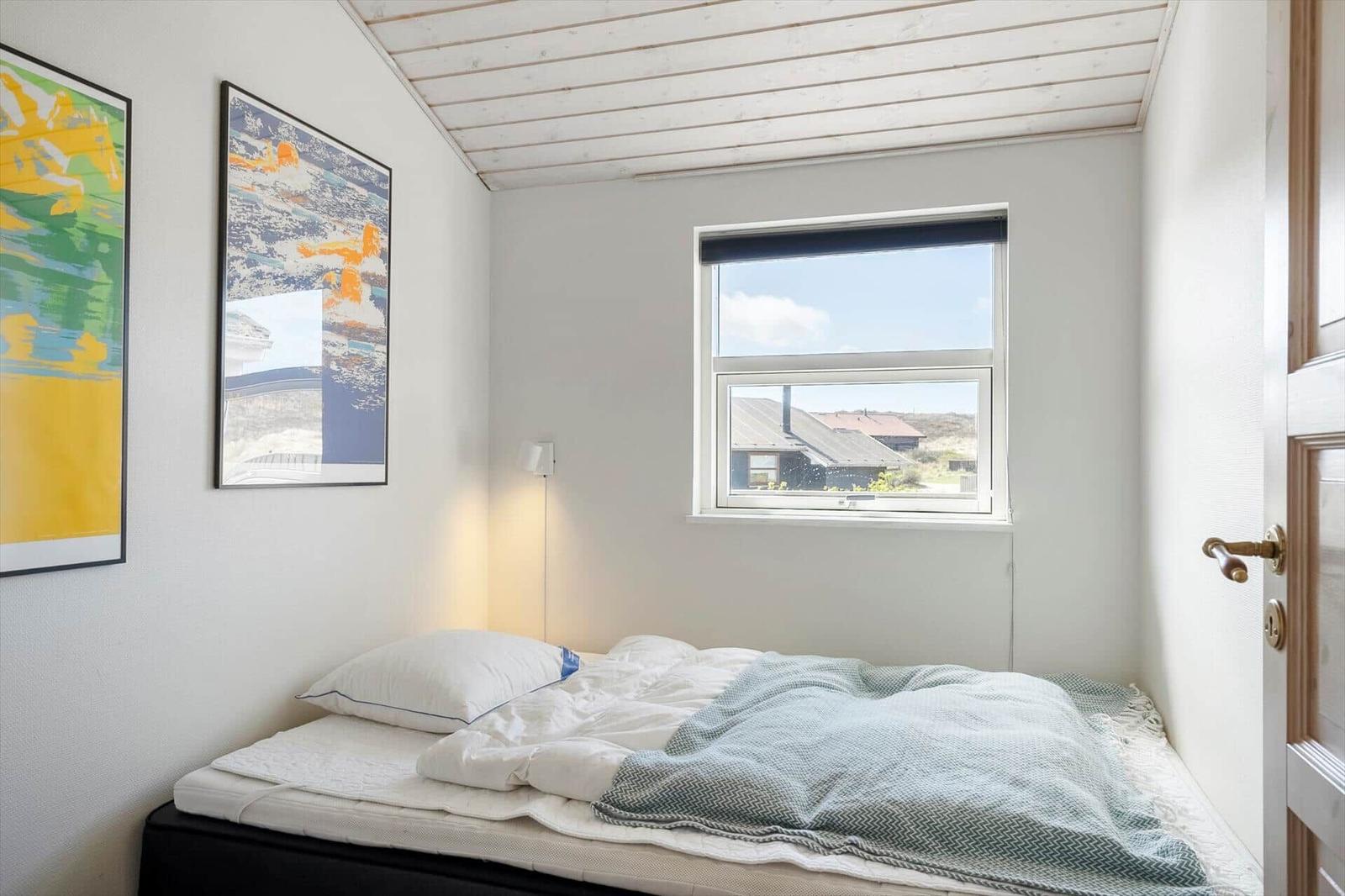 Bedroom with bed, window, and wall art.