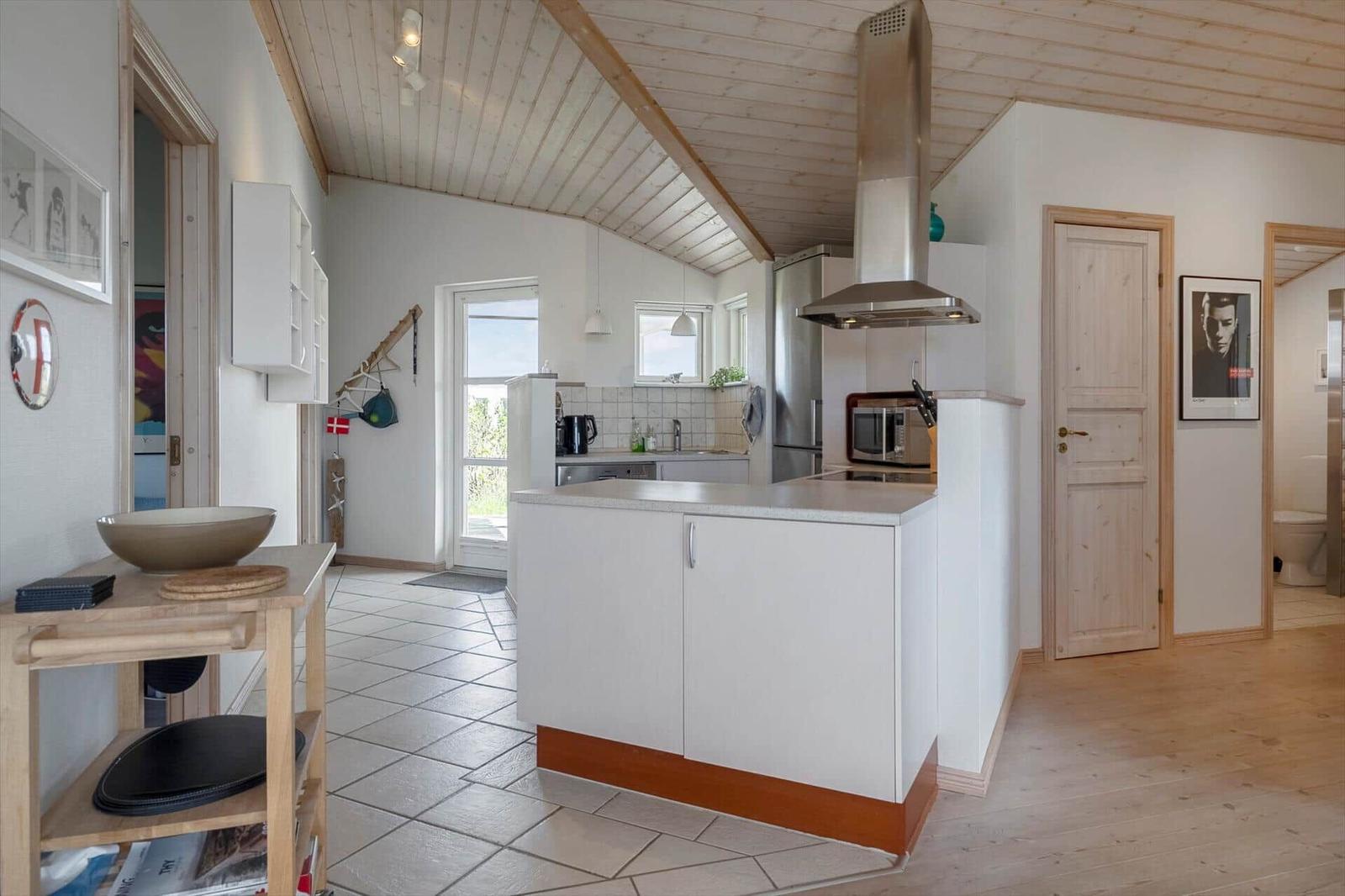 Kitchen with worktop, extractor hood, and kitchen units. Wooden ceiling and tiled floor.