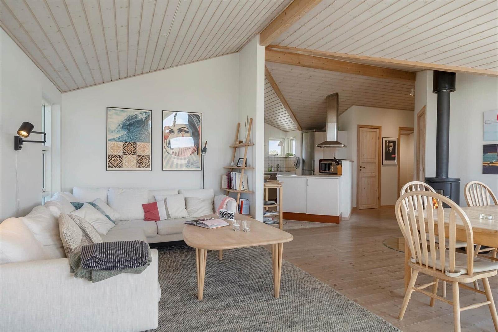 Living and dining area with sofa, table, and kitchen area in the background.