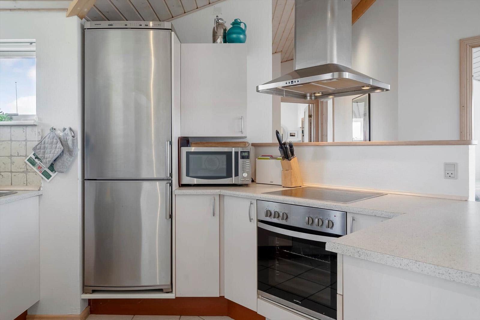 Kitchen with stainless steel fridge and oven, microwave, and range hood.