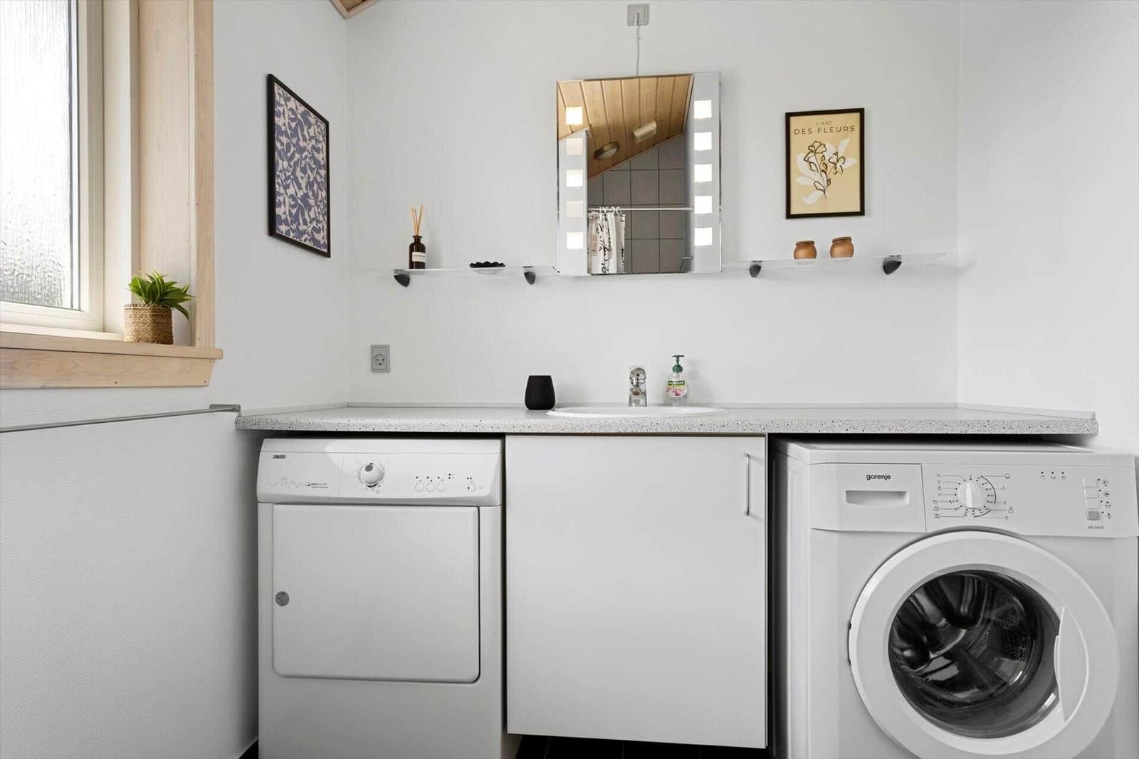 Waschmaschine und Trockner neben Waschbecken mit Spiegel