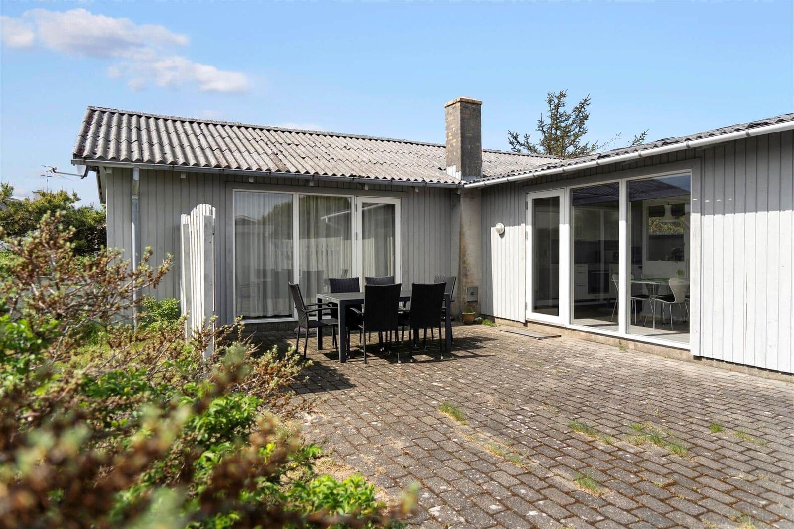 House with terrace, garden, and seating area. Through glass front to interior.