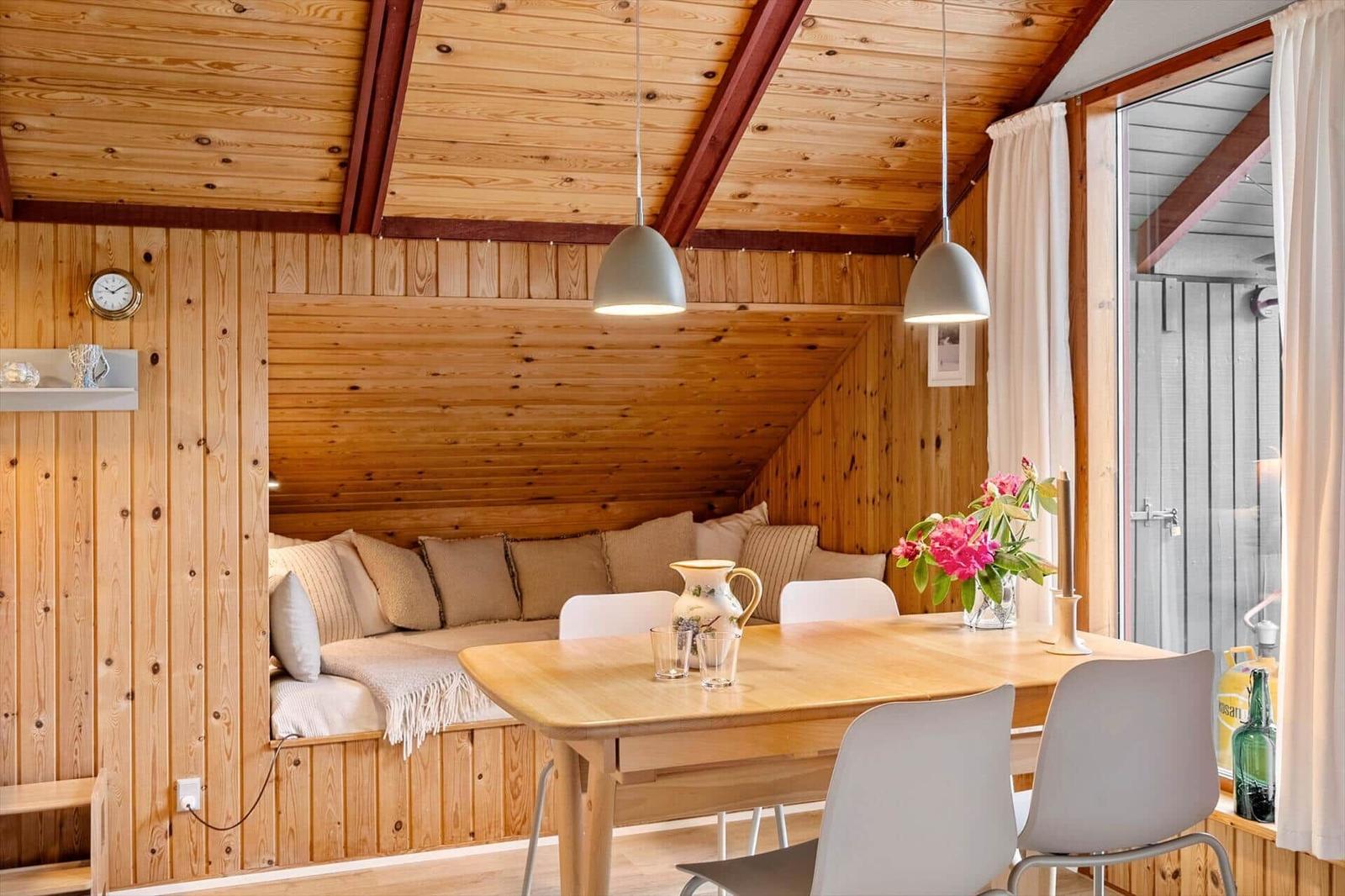 Esszimmer mit Holzwand, Tisch, Stühlen und Sitzbank unter Dachschräge