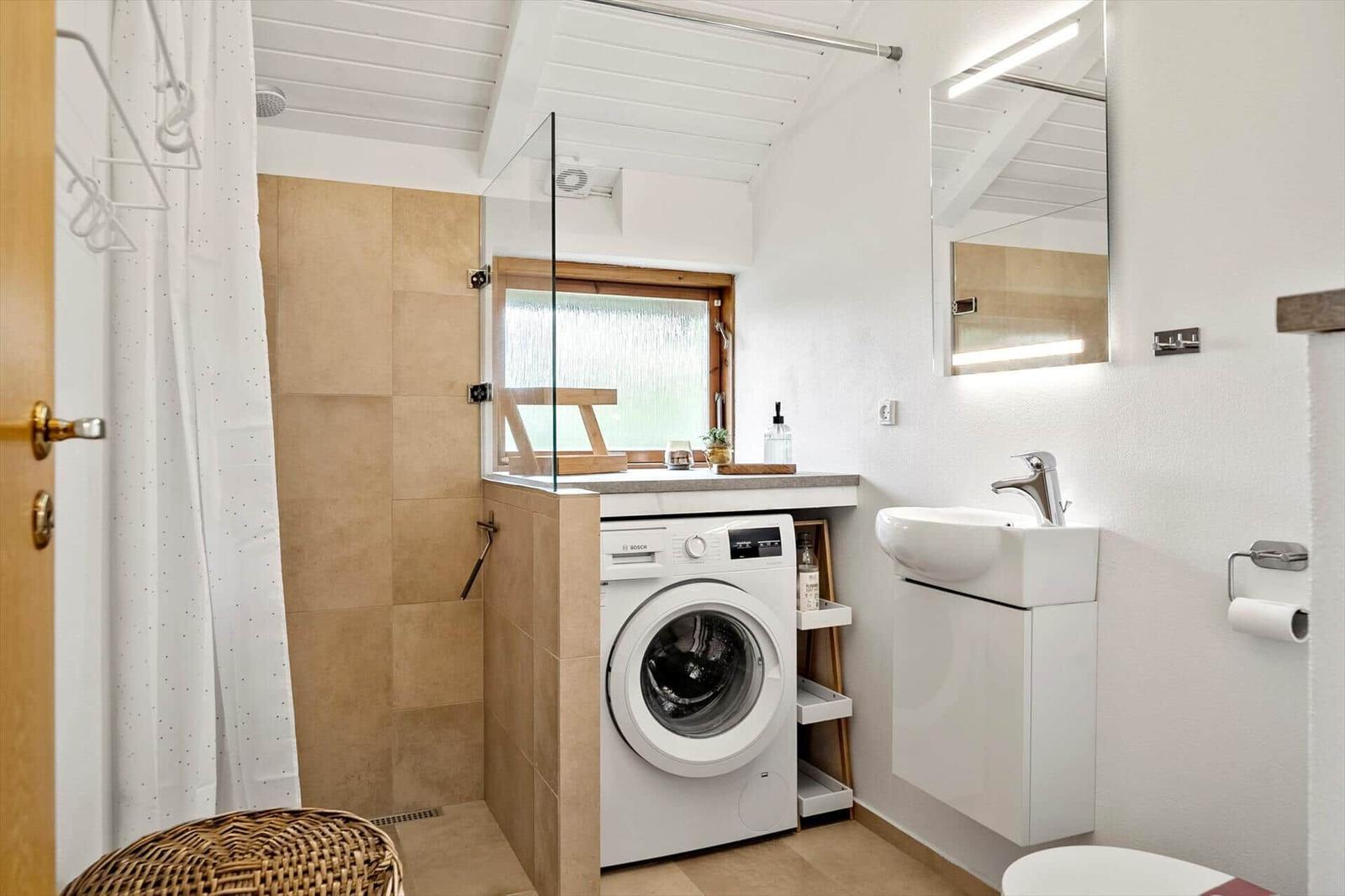 Badezimmer mit Dusche, Waschmaschine und Waschbecken