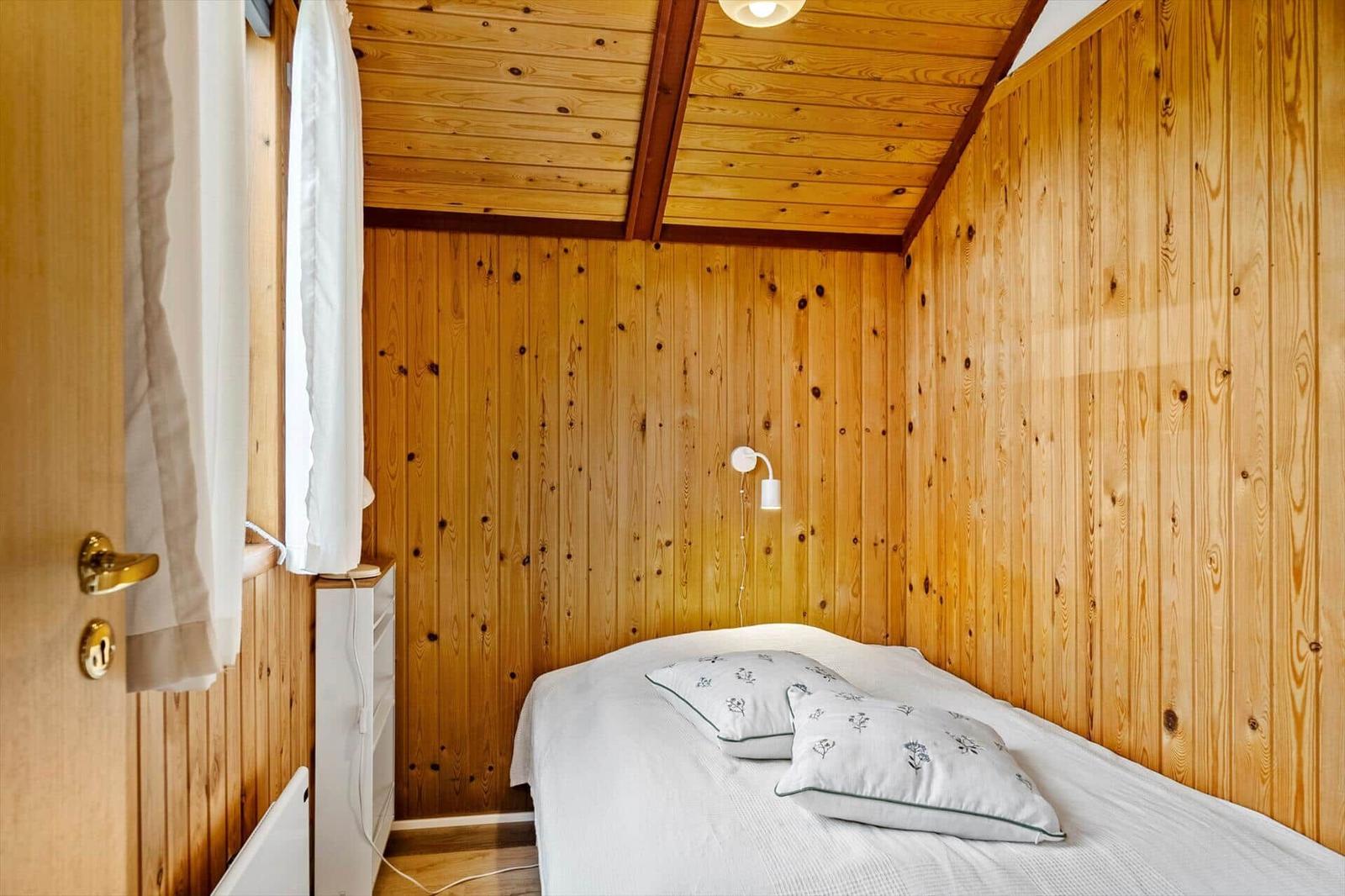 Ein Schlafzimmer mit Holzwänden, einem Bett und einer Wandlampe.