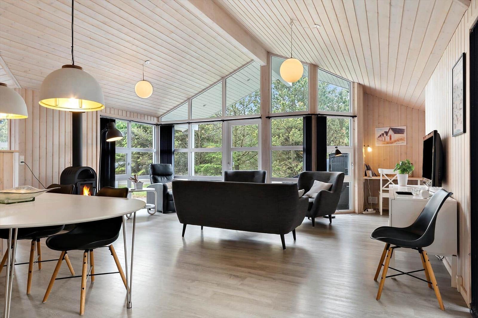 Großes Wohn- und Esszimmer mit Holzdecke, Fenstern und Kamin.