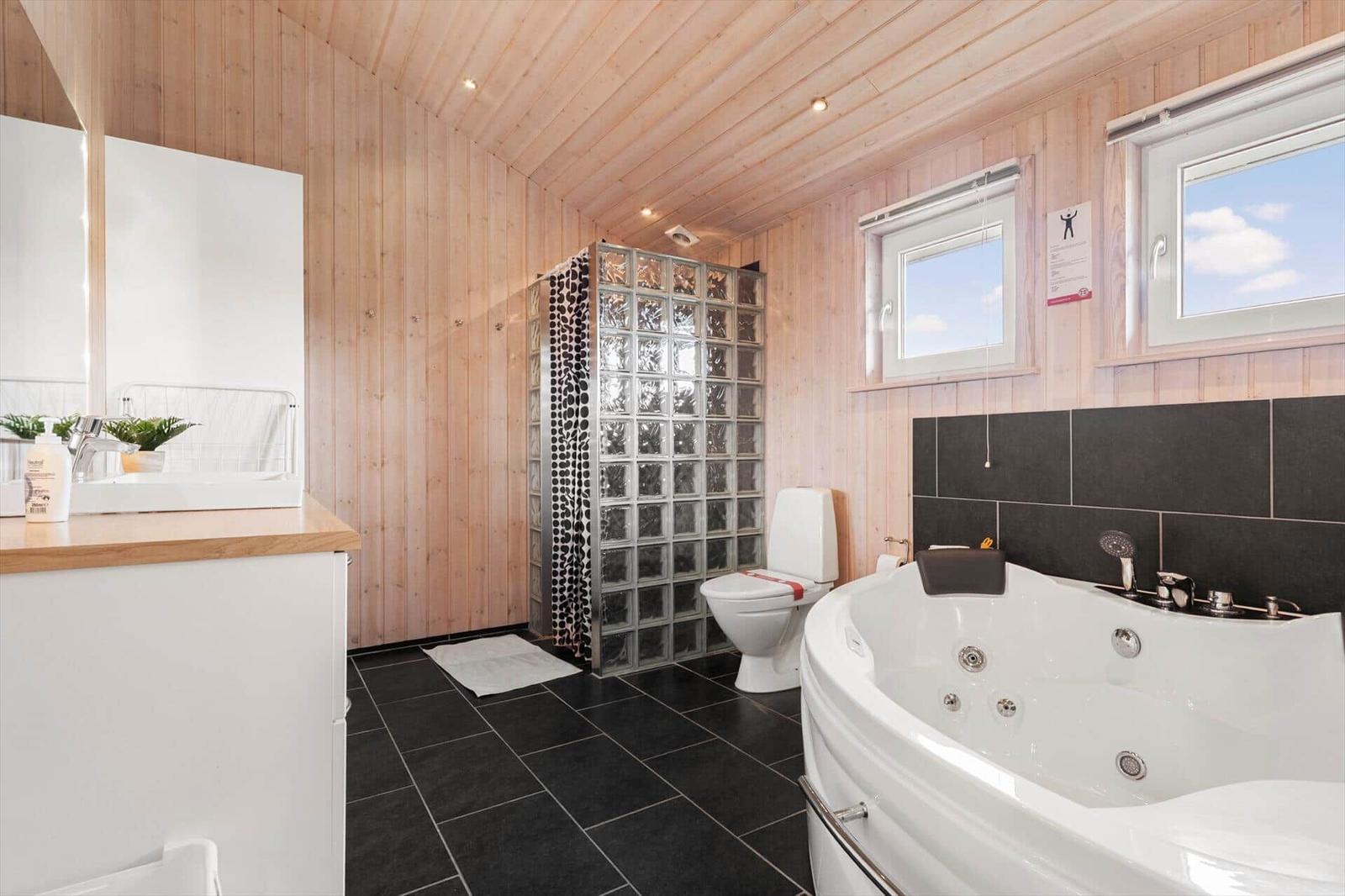 Badezimmer mit Badewanne, Toilette und Dusche aus Glasblöcken.