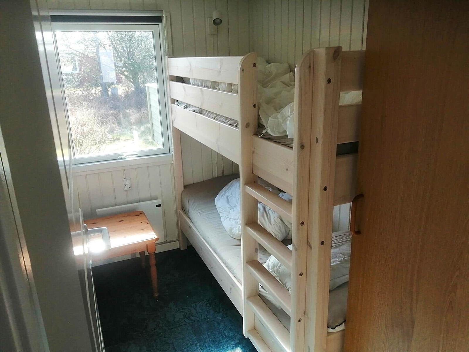 Zimmer mit Doppelstockbett, kleinem Tisch und Fenster mit Blick nach draußen.