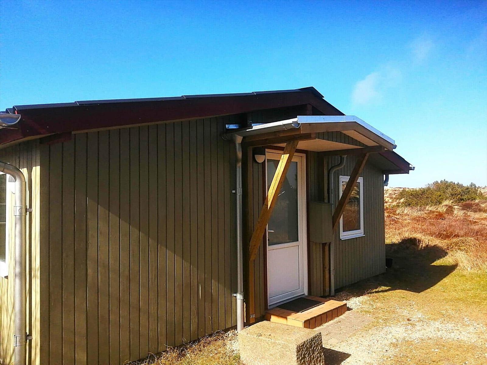 Holzhaus mit Eingangstür und Dachüberstand im Freien