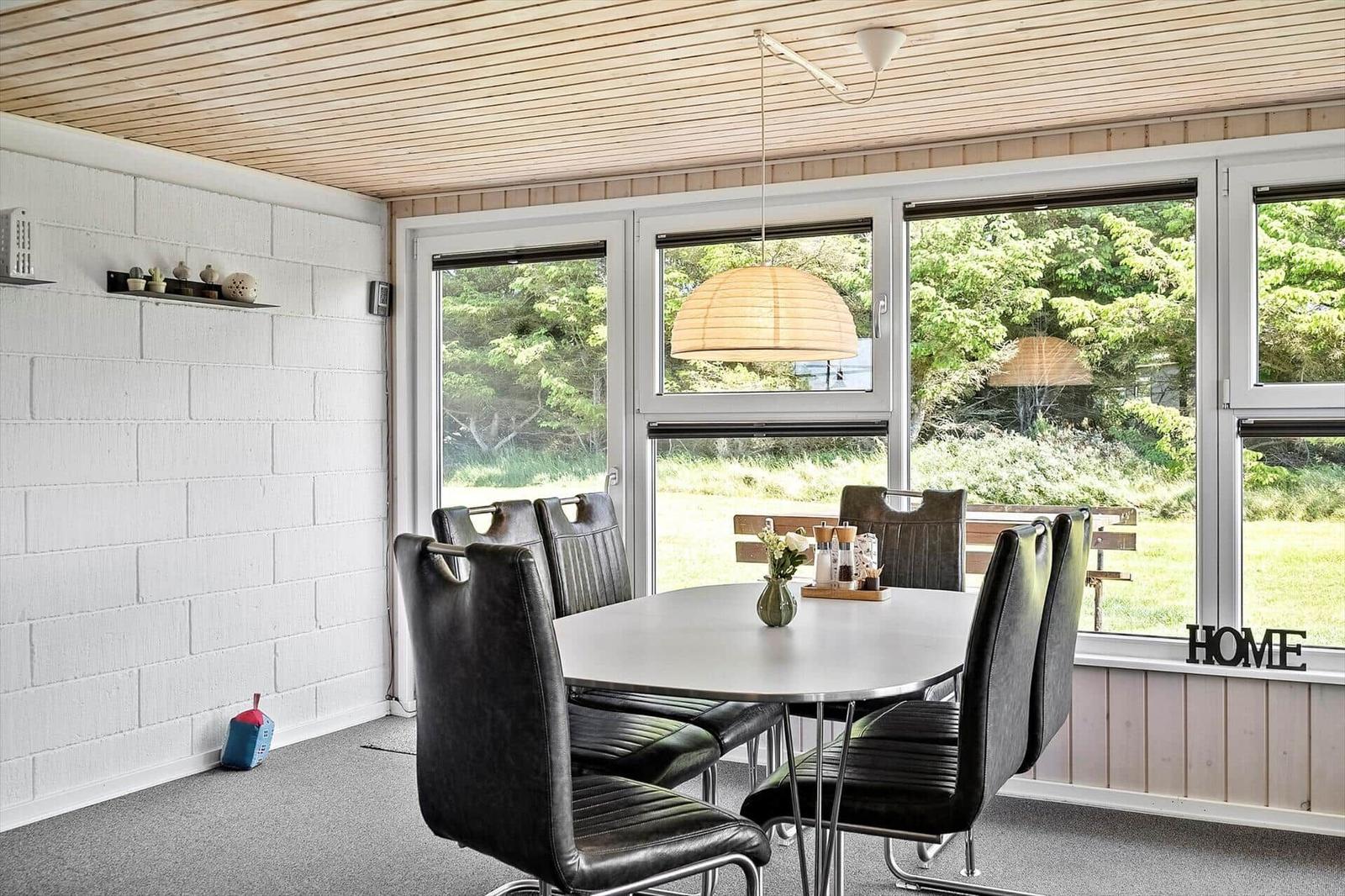 Dining room with round table, black chairs, and large window view of green area.