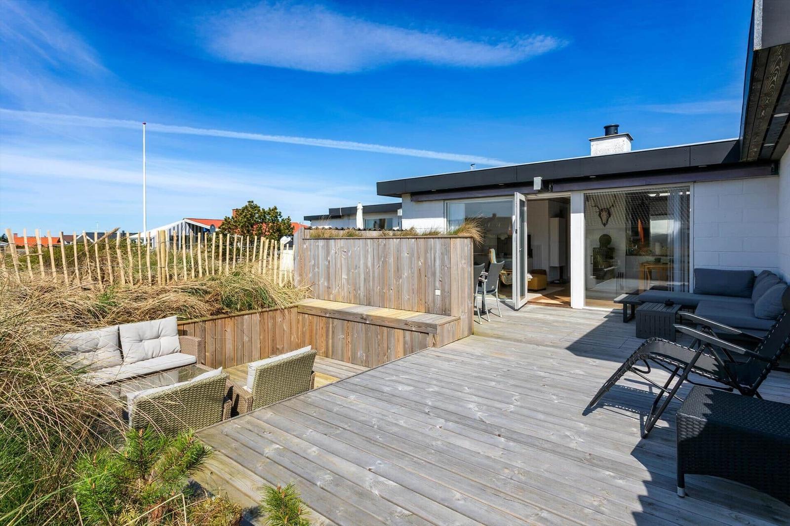 Terrasse mit Sitzgelegenheiten und Blick auf Stranddünen.