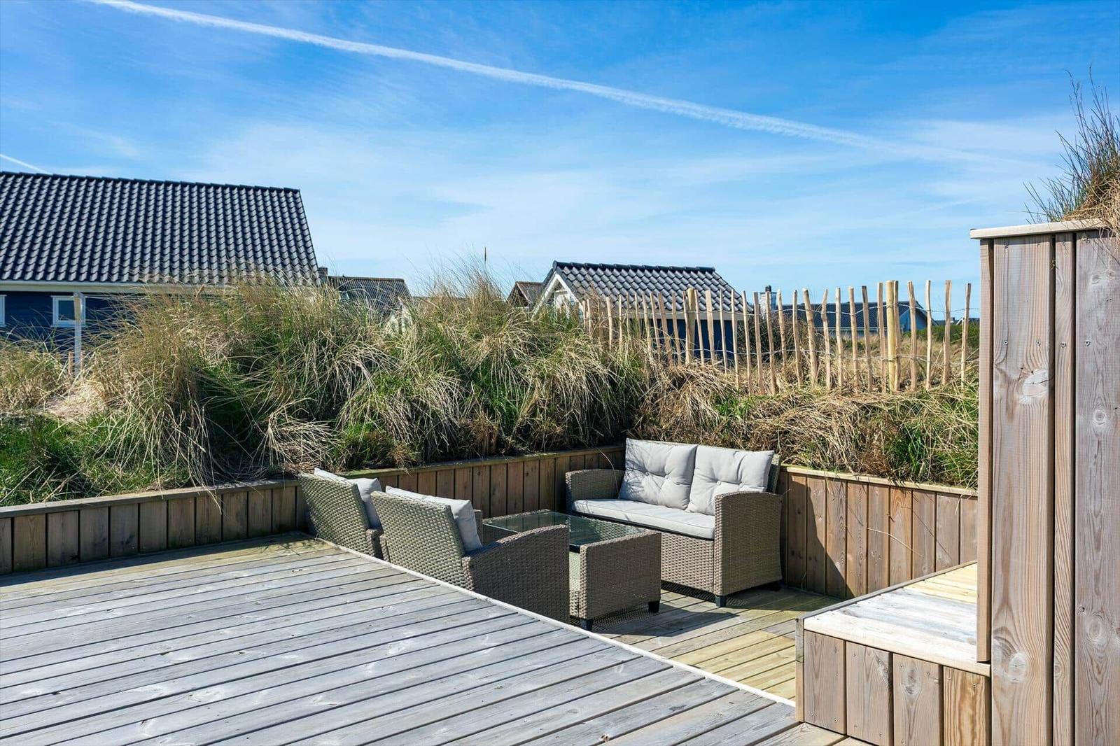Holzterrasse mit Sitzgruppe und Blick auf Dünen und Häuser