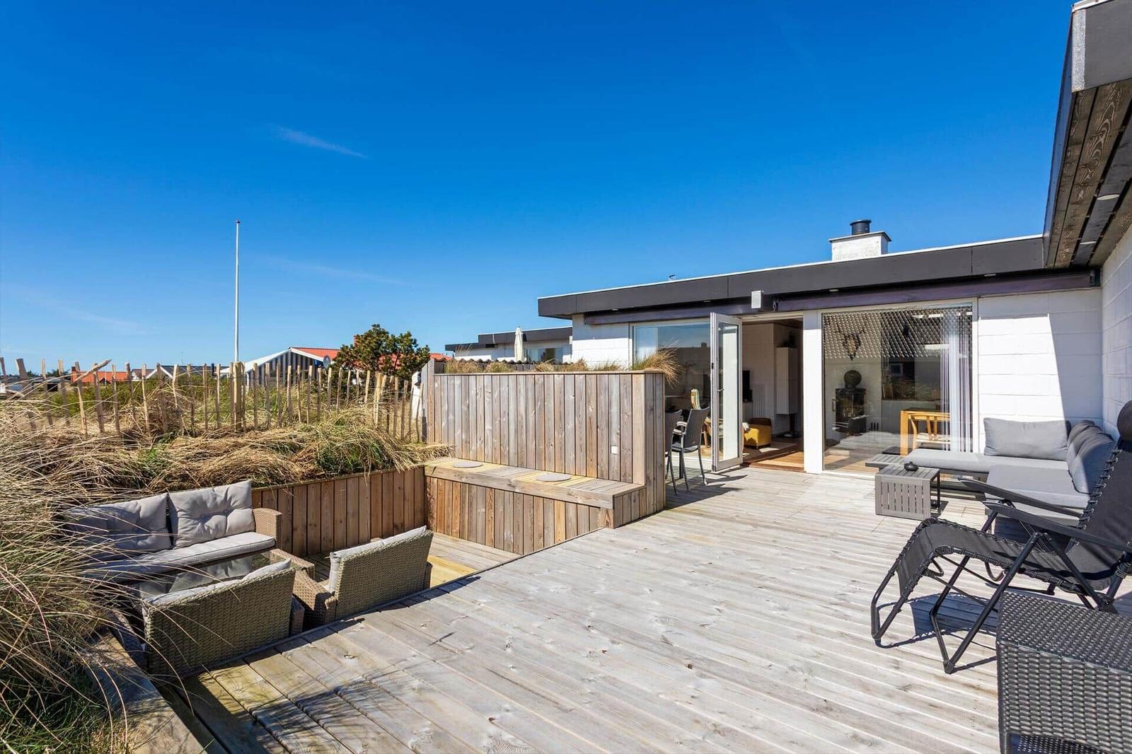 Terrasse mit Sitzgelegenheiten und Blick auf Strand und Himmel.