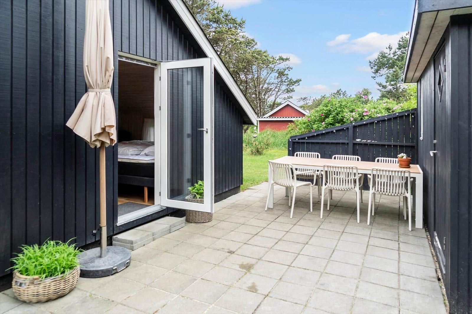 Terrace with table, chairs, and view of garden. Door leads to bedroom.