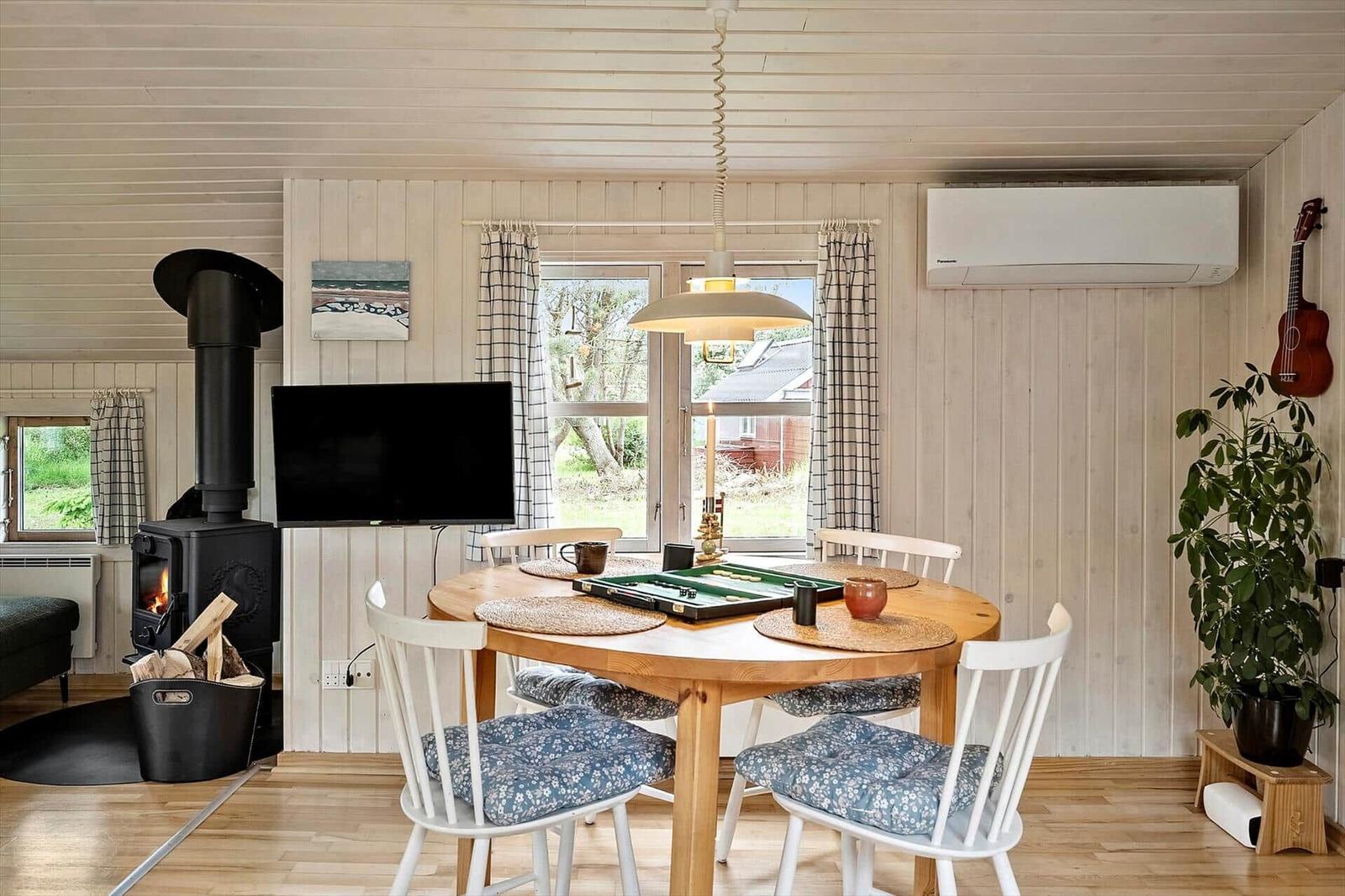 Dining room with wooden table, chairs, fireplace, and window view.