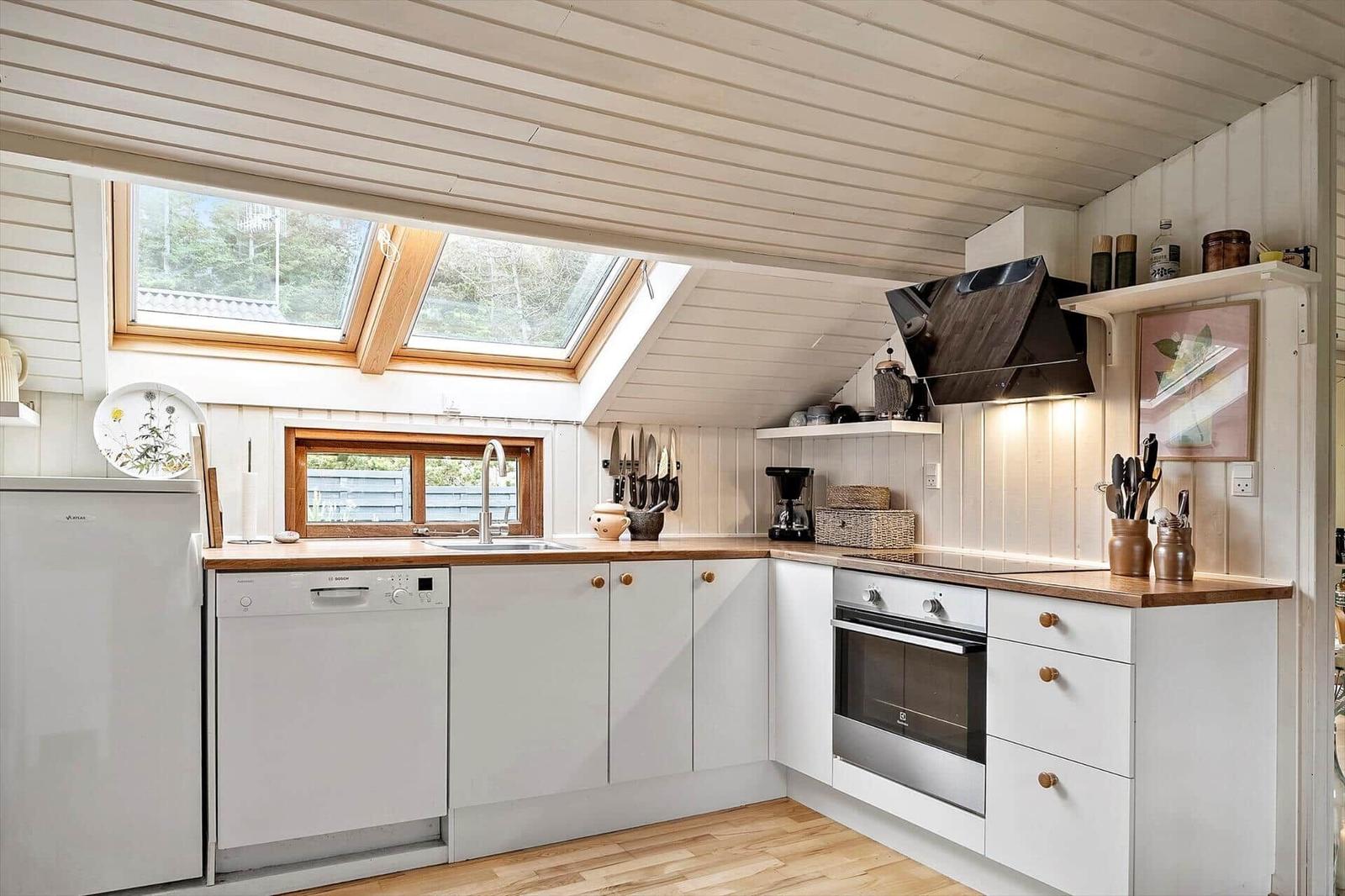 Kitchen with wooden surfaces, white cabinets, and skylights. Stainless steel appliances and kitchen utensils.
