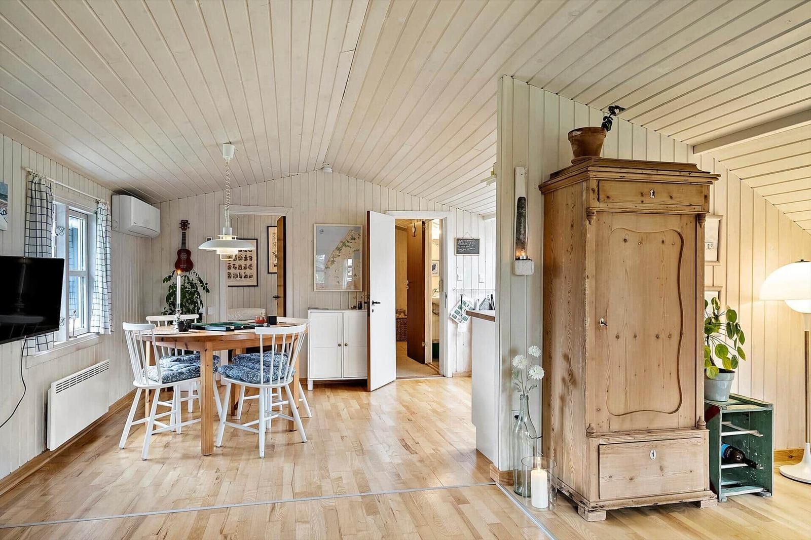 A room with dining area, hardwood floor, and antique wardrobe. A guitar hangs on the wall.